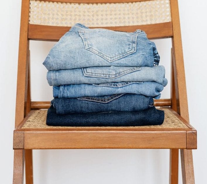 stack of blue jeans on chair